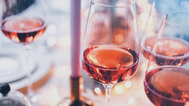Red wineglass filled with ros&eacute; surrounded by cozy candlelight and festive bokeh lights
