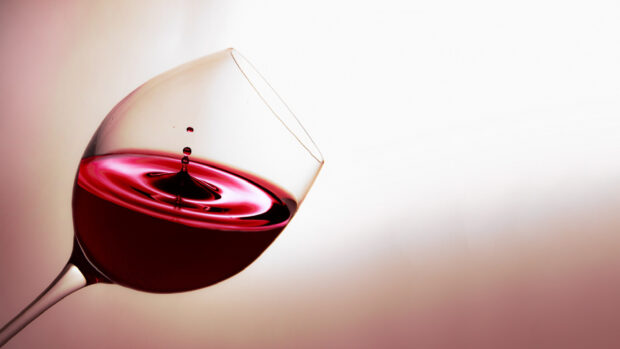 Red wineglass with liquid splash captured in motion