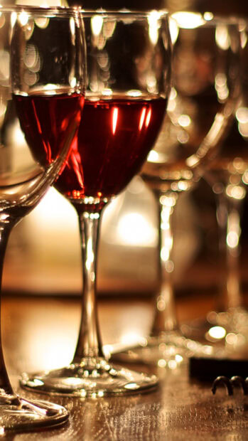 Red wineglass with bokeh lights on wooden table with other wineglasses