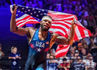 A wrestling athlete celebrating with USA flag in an intense wrestling match