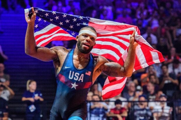 A wrestling athlete celebrating with USA flag in an intense wrestling match