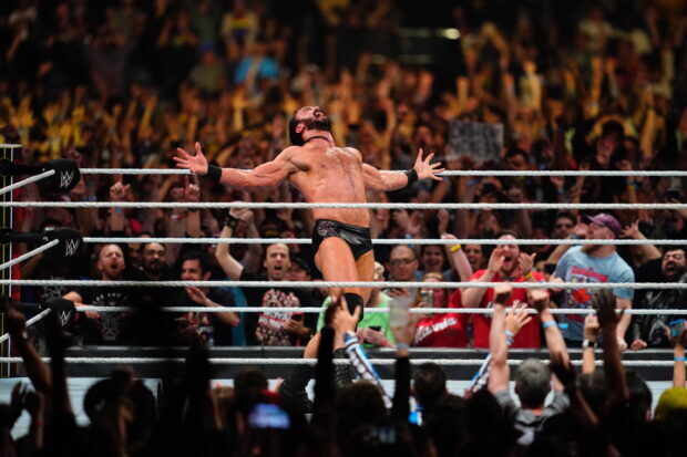 Wrestler celebrating victory in the ring with a cheering crowd in the background