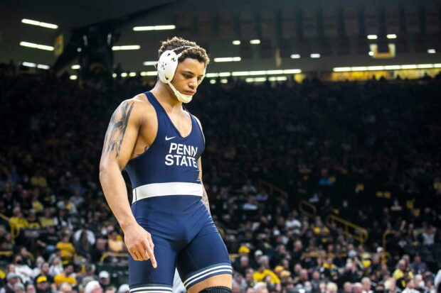 Wrestler from Penn State preparing for match in a packed stadium with tattoo on arm