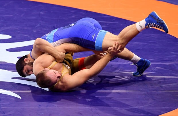 Two wrestlers in a wrestling match competing intensely on the mat