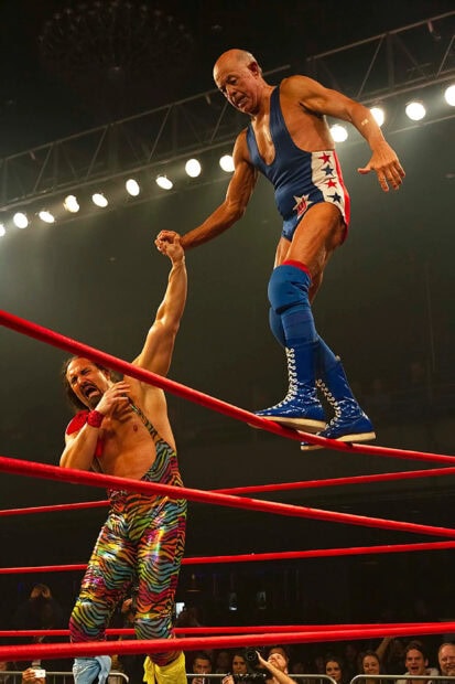 A senior wrestling athlete helping his opponent to stand in the ring during a match