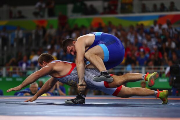 Male athlete performing a wrestling move in a competitive match on the mat