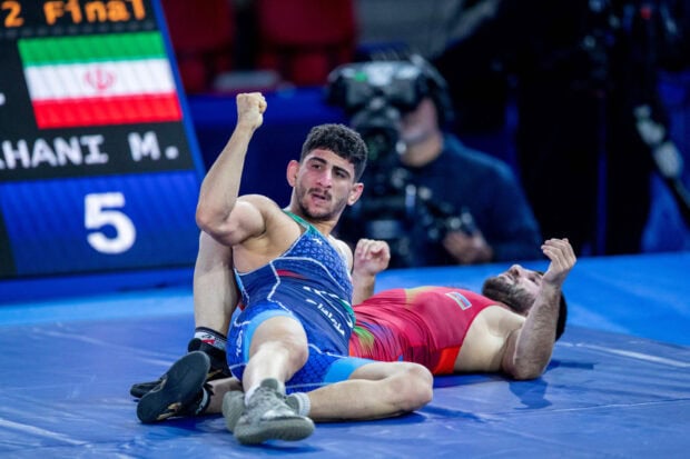 Wrestler celebrating victory on the mat after a wrestling match with opponent lying down