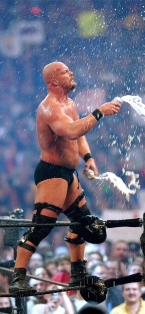 Wrestler performing a wrestling move while spraying water in the ring during a match