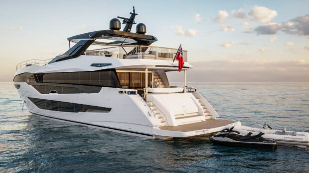 Modern yacht docked on calm sea with jet ski and clear sky at sunset