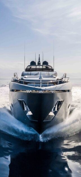 Modern yacht cutting through the sea with powerful waves around the bow