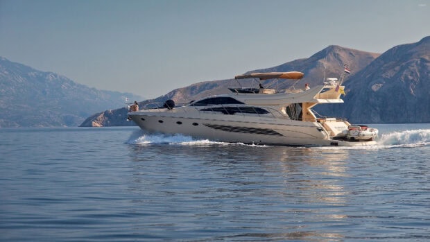 A luxury yacht cruising on calm sea water with mountainous background