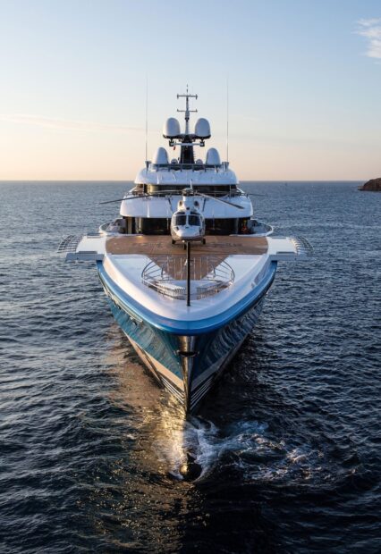 Luxury yacht sailing on calm ocean water with a helicopter on the deck