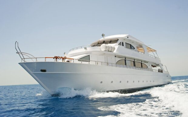 A luxury yacht cruising on the ocean with clear blue skies above