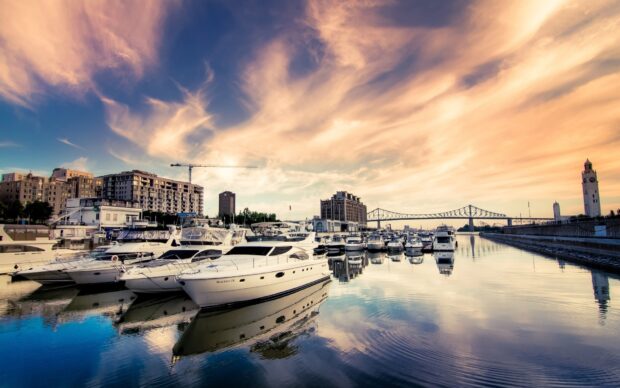 A marina filled with luxury yachts docked under a vibrant sunset sky in the city harbor