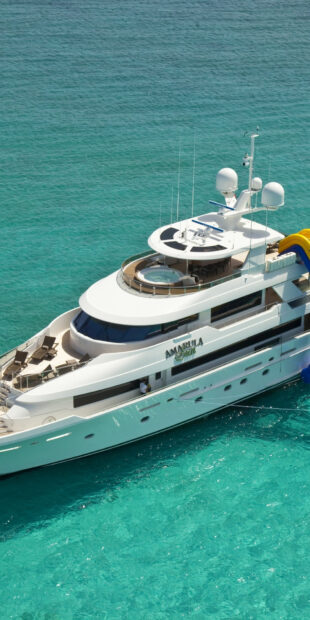 Luxury yacht cruising on clear turquoise water with a hot tub on the deck