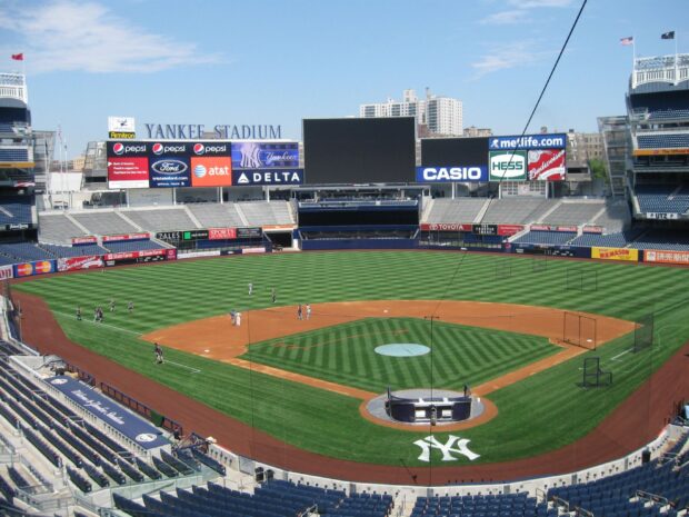 The iconic Yankee Stadium field with players practicing on the grass in the large baseball park