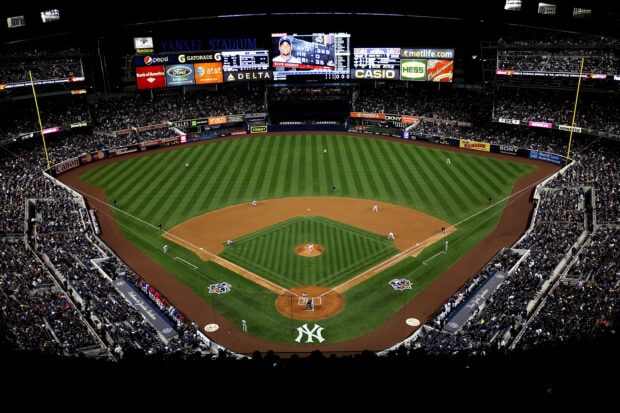 A panoramic view of Yankee Stadium during a baseball game with players on the field and a large crowd in the stands