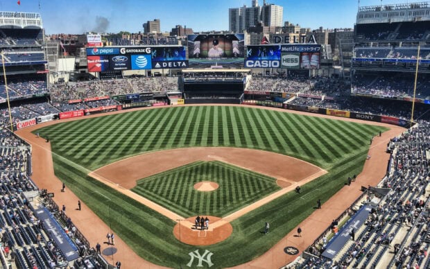 A baseball field at Yankee Stadium with prepared pitch and spectators in the stands