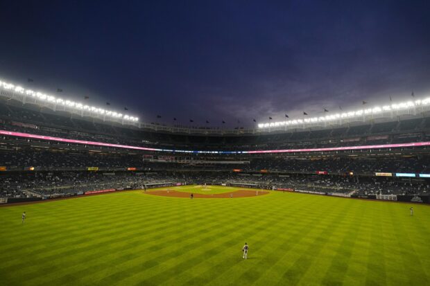 A view of Yankee Stadium field with baseball players during a game at night