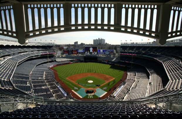 A wide view of Yankee Stadium featuring the baseball field and seating areas in bright daylight