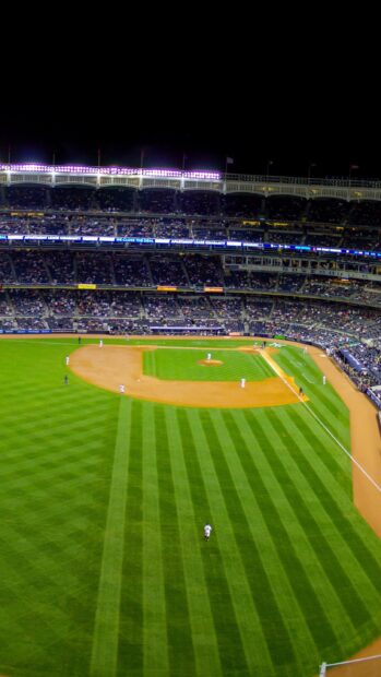 A night view of Yankee Stadium with players on the field and spectators in the stands