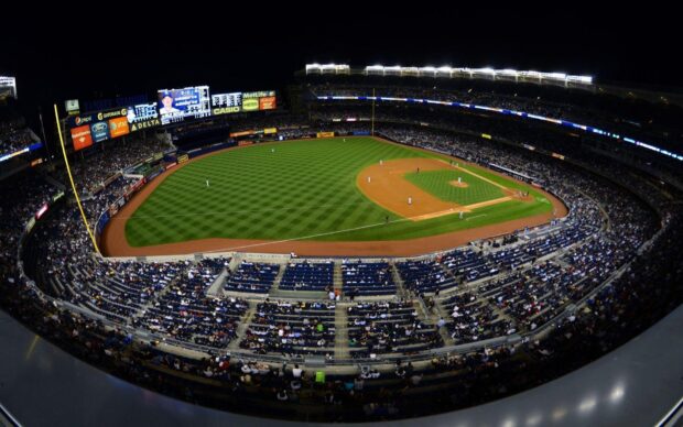 A wide view of Yankee Stadium showing the baseball field and the crowd at a night game