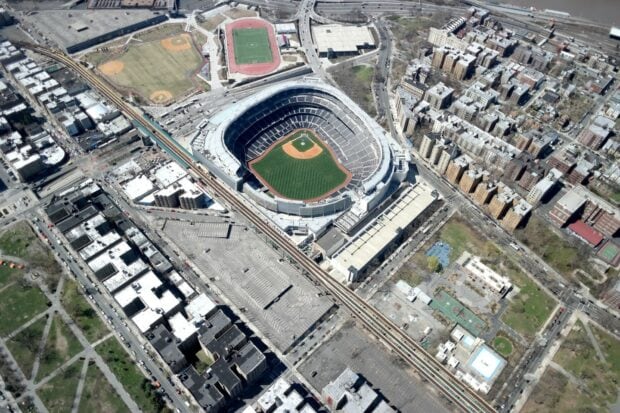 Aerial view of Yankee Stadium surrounded by urban buildings and sports fields