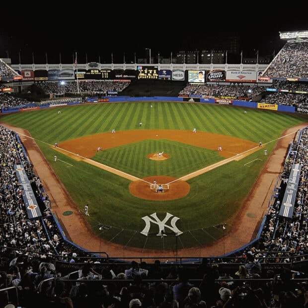 Nighttime view of Yankee Stadium with players on the field and crowd in the stands