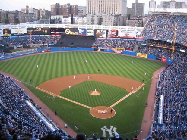 A panoramic view of Yankee Stadium during a baseball game with green field and players on the diamond