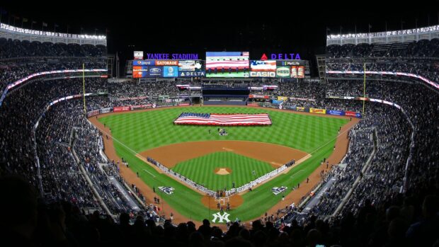 A panoramic view of Yankee Stadium field showing the American flag and teams lined up before the game