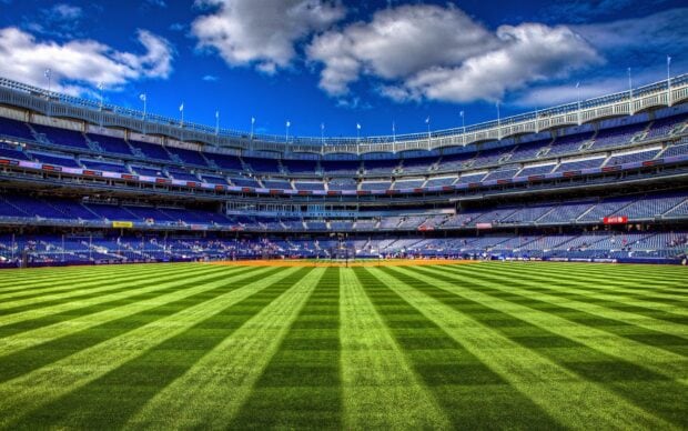 A panoramic view of Yankee Stadium showing the green field and empty stands in clear daylight