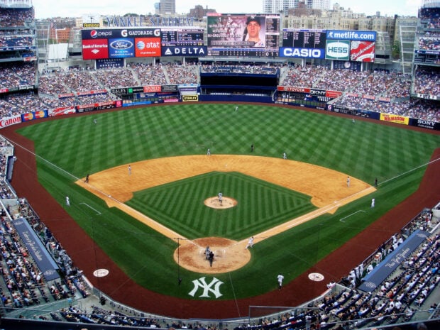 A baseball game in progress at Yankee Stadium with players on the field and fans in the stands