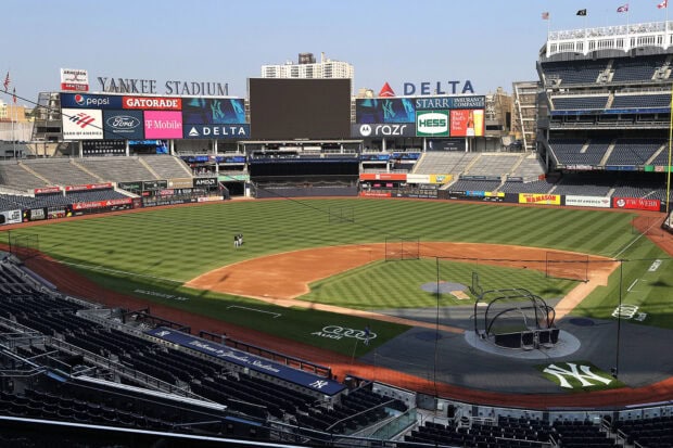 A wide view of Yankee Stadium baseball field during the day with empty stands and batting practice setup