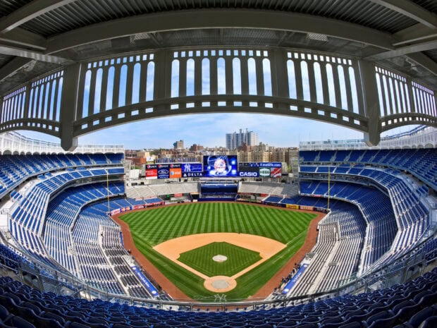 A panoramic view of Yankee Stadium with clear skies and empty seats in the baseball field