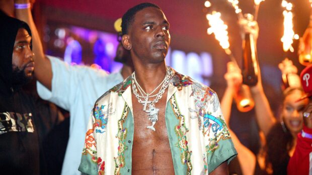 Young Dolph wearing a colorful shirt with chains at a lively party scene