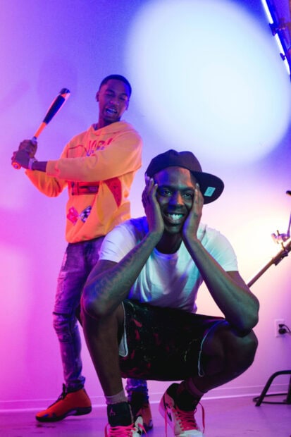 Young Dolph and a friend enjoying a playful moment in a colorful room with vibrant lighting