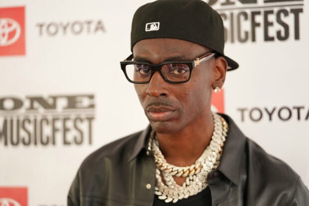 Young Dolph wearing black cap and glasses with diamond chains at an event