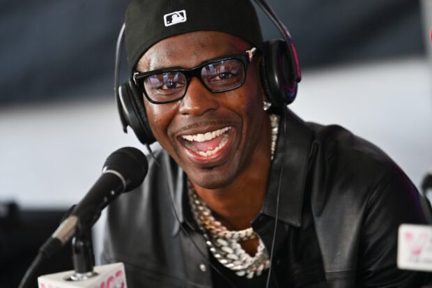 Young Dolph wearing glasses and headphones smiling during a microphone interview