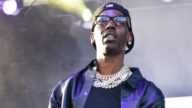 Young Dolph wearing chains and glasses during a live performance on stage