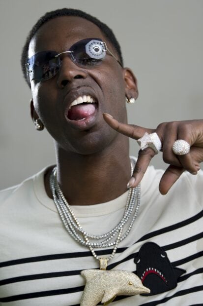 Young Dolph wearing diamond chains and sunglasses showing hand gesture close up