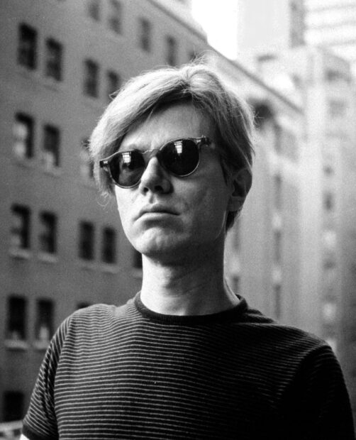 Black and white portrait of Andy Warhol wearing sunglasses and striped shirt
