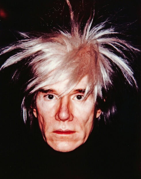 Close up of Andy Warhol with spiky white hair and serious expression