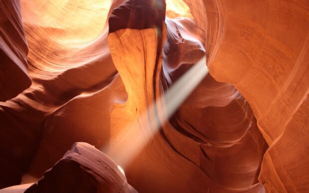 Natural light beam shining through Antelope Canyon rock formations creating warm orange tones