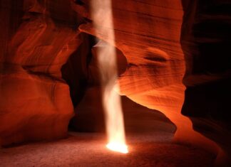 A stunning rock formation inside Antelope Canyon with a beam of light shining down onto the floor