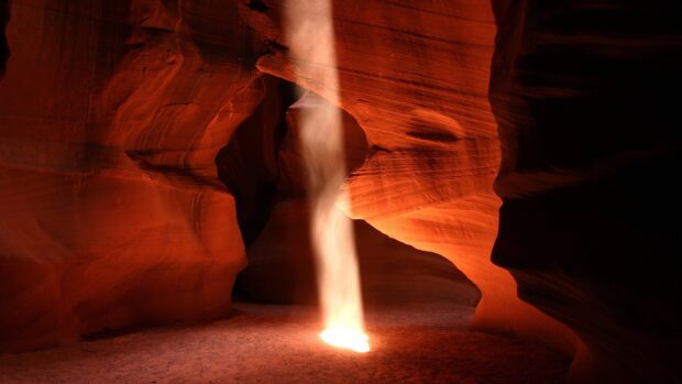 A stunning rock formation inside Antelope Canyon with a beam of light shining down onto the floor