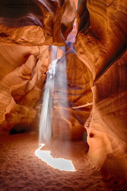 Sunlight beams penetrate the beautiful sandstone walls of Antelope Canyon creating a glowing path on the sandy floor