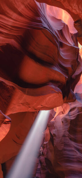 A stunning beam of light shining through red rock formations in Antelope Canyon