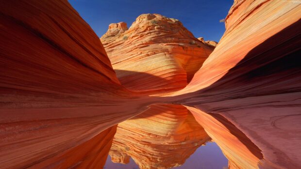 The natural rock formations with smooth layered stones and reflection in water at Antelope Canyon
