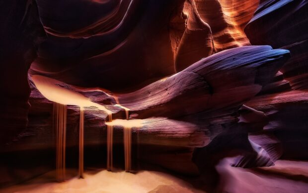 Smooth flowing sand inside the Antelope Canyon showcasing natural rock formations and light beams