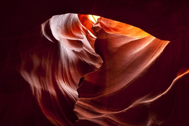 Smooth sandstone formations inside Antelope Canyon with vibrant light beams and natural curves